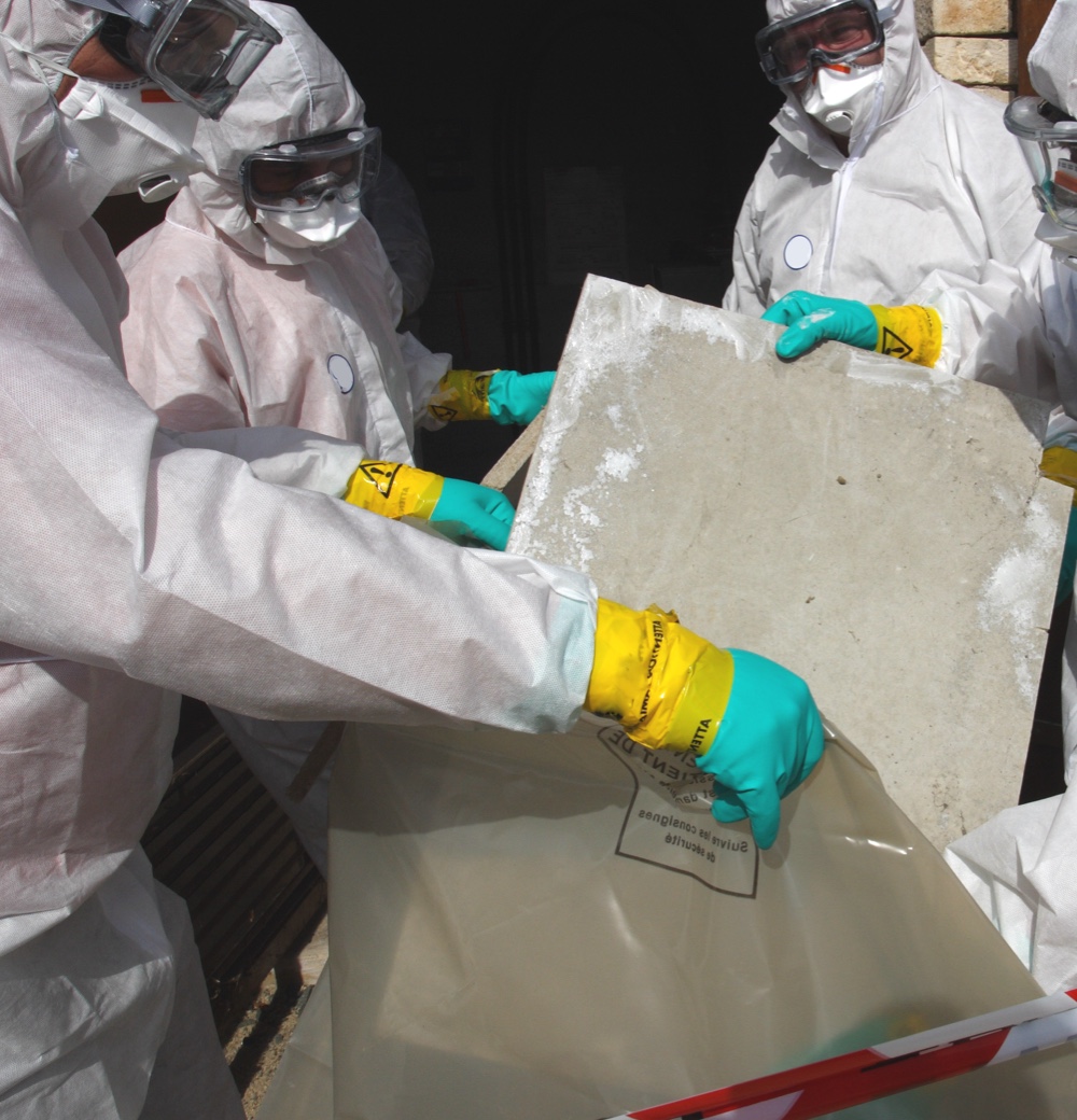 Careful removal of asbestos materials by professionals wearing protective gear