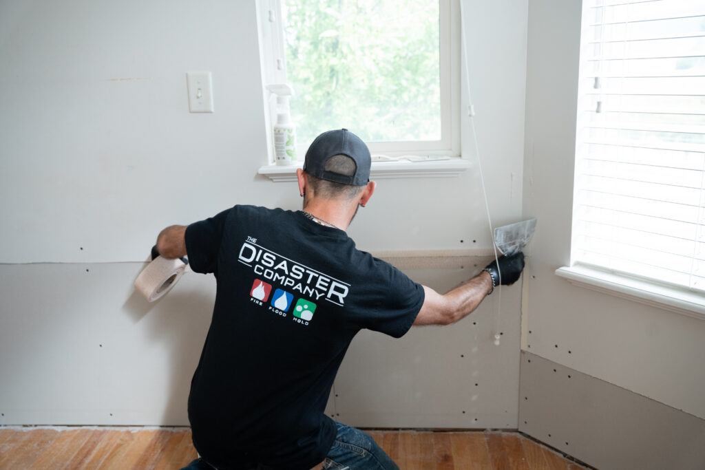 Disaster Company technician taping a drywall seam during a water damage repair