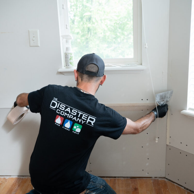 Disaster Company technician taping a drywall seam during a water damage repair